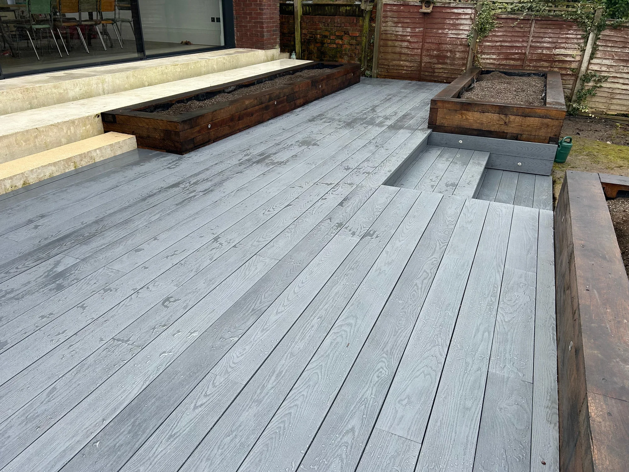 Grey composite decking surrounded by railway-sleeper raised flower beds