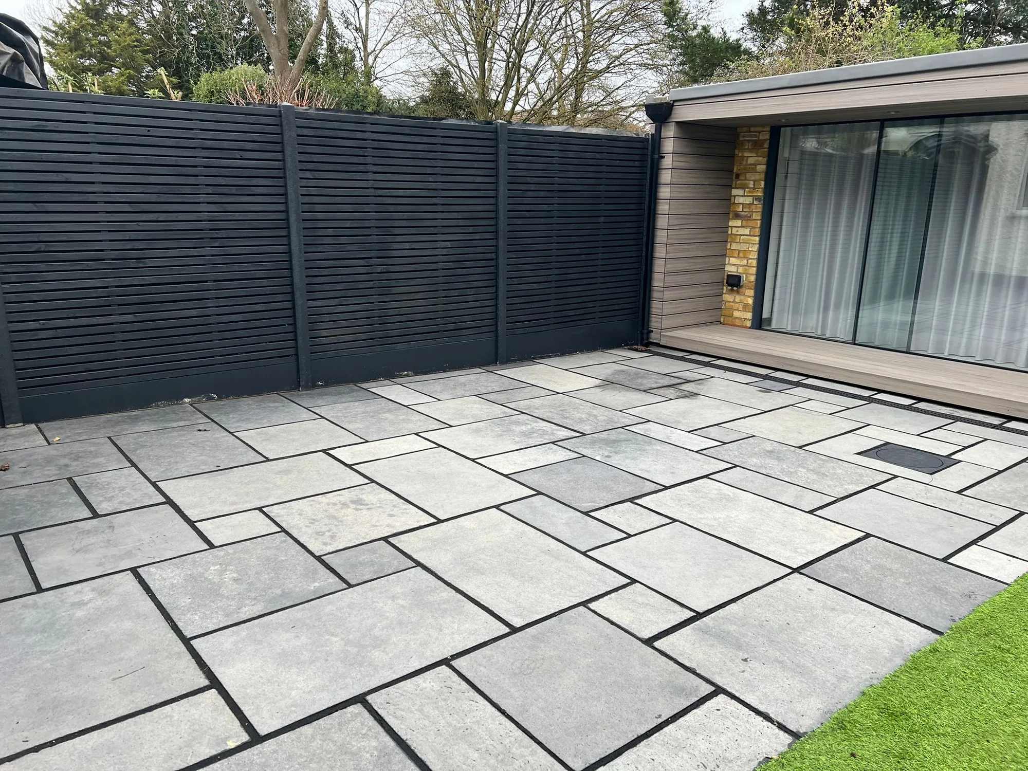 Stone-paved London courtyard with dark slatted fencing