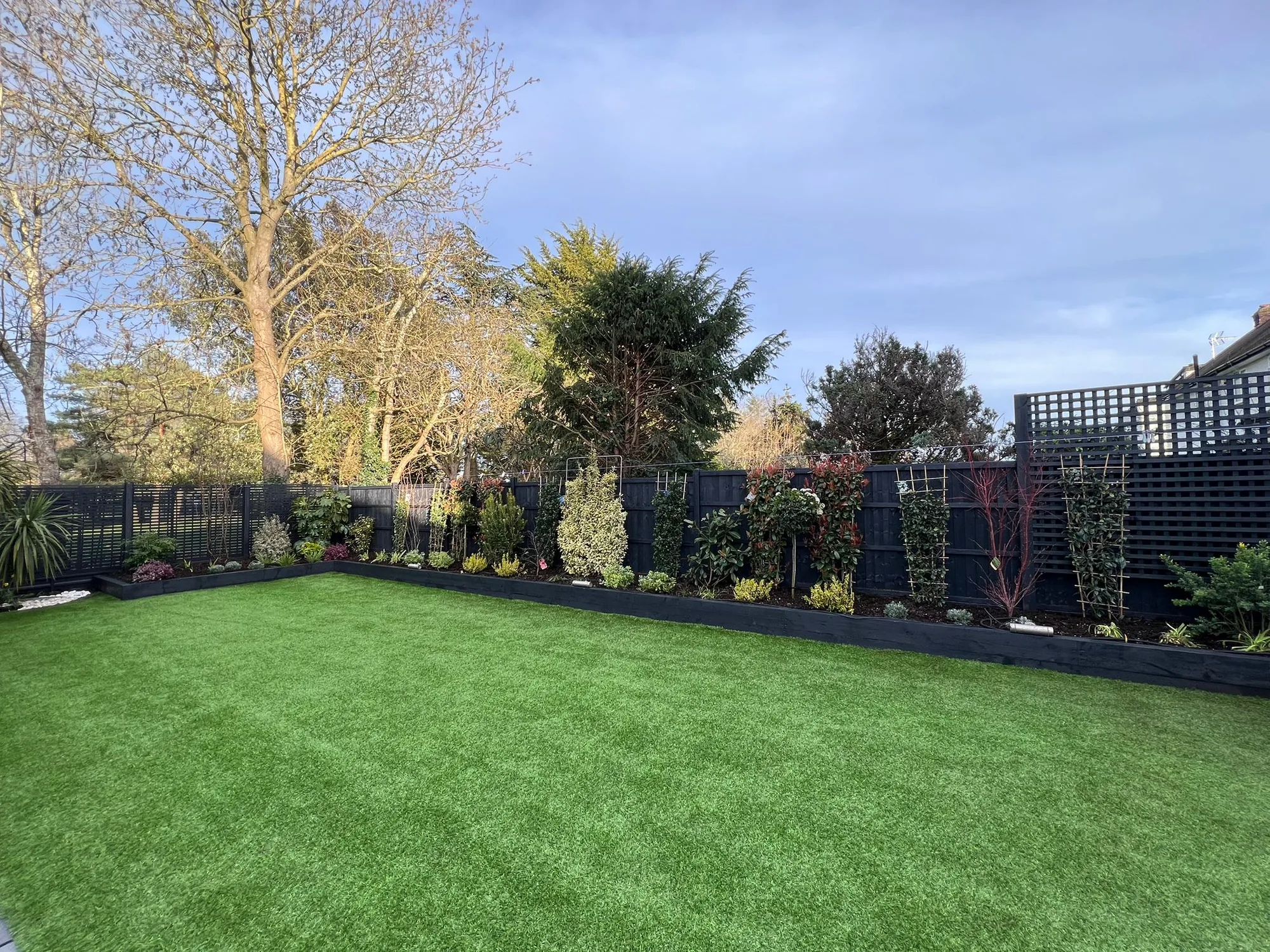 Clean lawn bordered by a black-painted timber fence and Chelsea trellises in Finchley